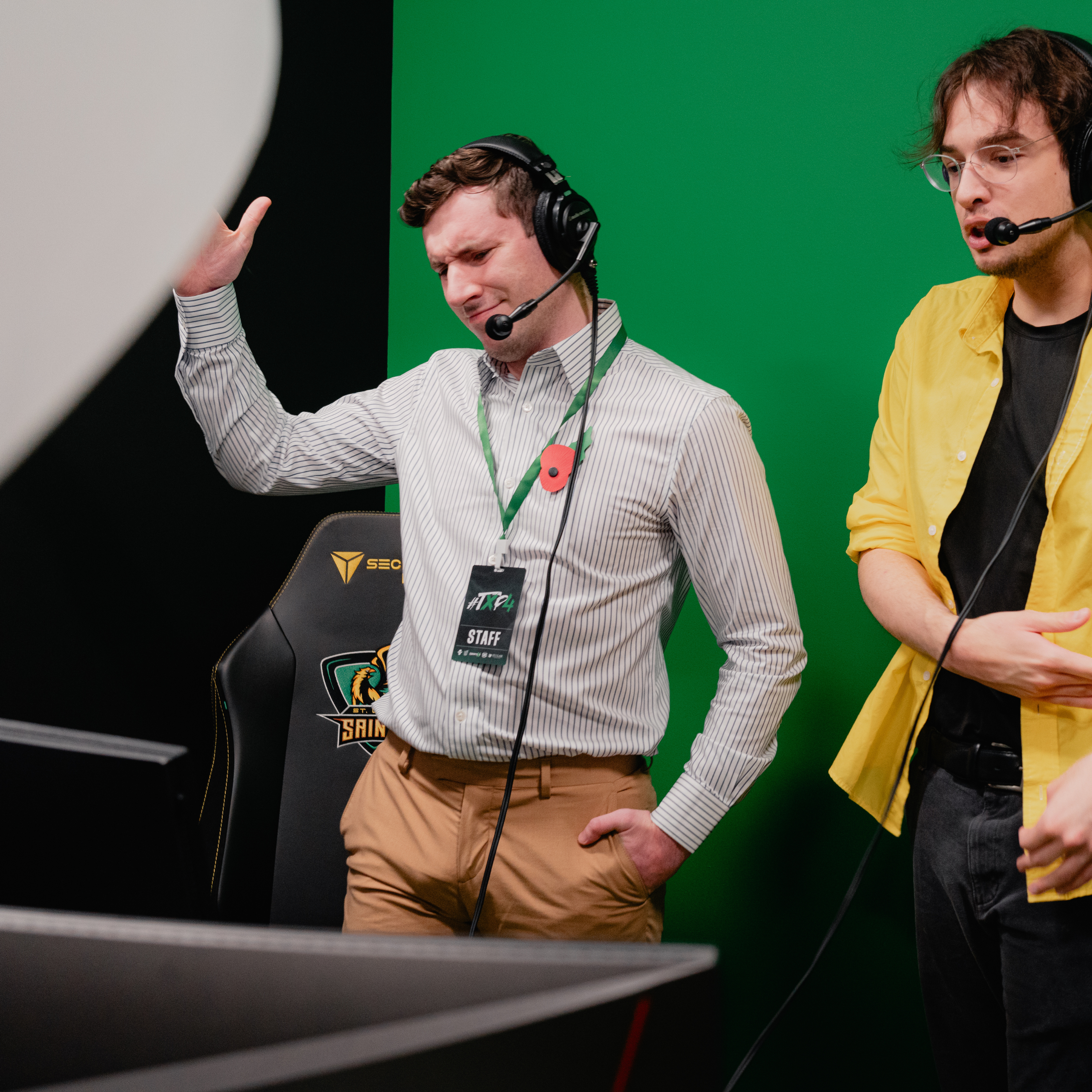 Two people wearing headsets, event badges and lanyards at an esports venue